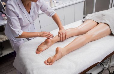 Güzeller güzeli genç bir kadın spa salonunda bacak masajı yapıyor. Kozmetoloji kavramı