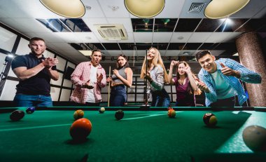 Bilardo oynayan bir grup neşeli genç arkadaş. İşten sonra eğlenceli zamanlar.