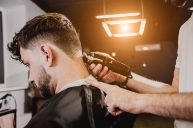 Berber dükkanında son moda saç kesimi olan genç bir adam. Berber saç ve sakal kesimi yapıyor. Berber dükkanı kavramı.