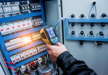 Fünye kutusundaki sıcaklığı kontrol etmek için kızılötesi termal görüntüleme kamerası kullanan teknisyenleri kapat