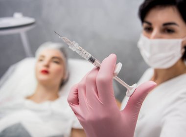 Doktor kozmetik uzmanı yüz enjeksiyonu prosedürünü uygular. Güzellik salonunda genç bir kadın. Kozmetoloji kavramı.