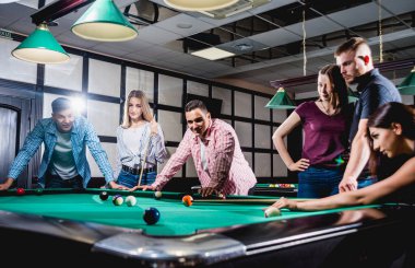 Bilardo oynayan bir grup neşeli genç arkadaş. İşten sonra eğlenceli zamanlar.