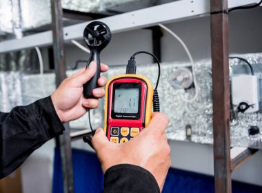 Teknisyen, hava akışı ölçümlerini elle ölçen anemometre kullanıyor