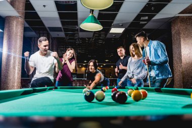 Bilardo oynayan bir grup neşeli genç arkadaş. İşten sonra eğlenceli zamanlar.