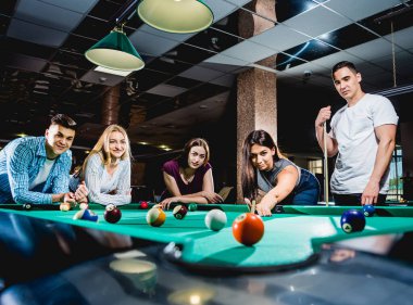 Bilardo oynayan bir grup neşeli genç arkadaş. İşten sonra eğlenceli zamanlar.