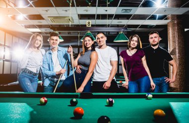 Bilardo oynayan bir grup neşeli genç arkadaş. İşten sonra eğlenceli zamanlar.