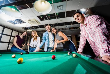 Bilardo oynayan bir grup neşeli genç arkadaş. İşten sonra eğlenceli zamanlar.