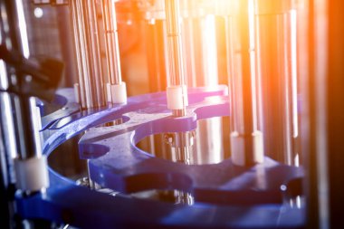 Otomatik doldurma makinesi plastik şişelere su dolduruyor, endüstriyel arka plan