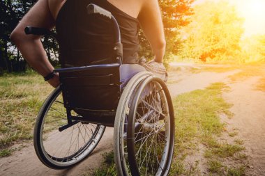 Kamp alanında arkadaşlarıyla dinlenen engelli bir adam. Çadırların arka planında, ormanda tekerlekli sandalye. Kamp yapmak. Yaz zamanı.