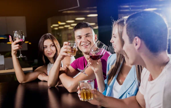 Cheerful friends in the pub. Drinking beer, wine and whisky, talking, having fun. Meeting friends after work