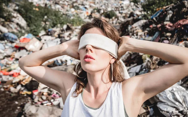 blindfolded female volunteer screams from powerlessness in dump of plastic rubbish