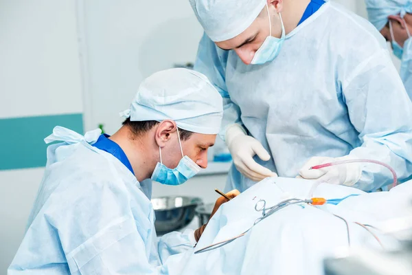 Brain surgery. Group of surgeons in operating room with surgery equipment.