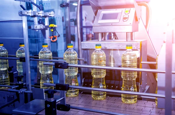 Bottling line of sunflower oil in bottles at plant, high technology concept, industrial background