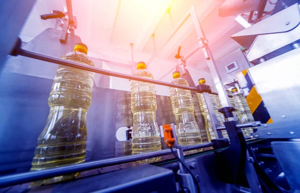 Bottling line of sunflower oil in bottles at plant, high technology concept, industrial background