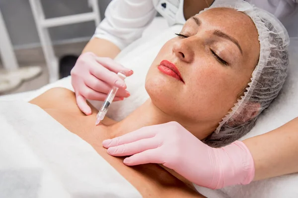 De arts cosmetoloog maakt de neklijn injecties procedure. Jonge vrouw in een schoonheidssalon. — Stockfoto