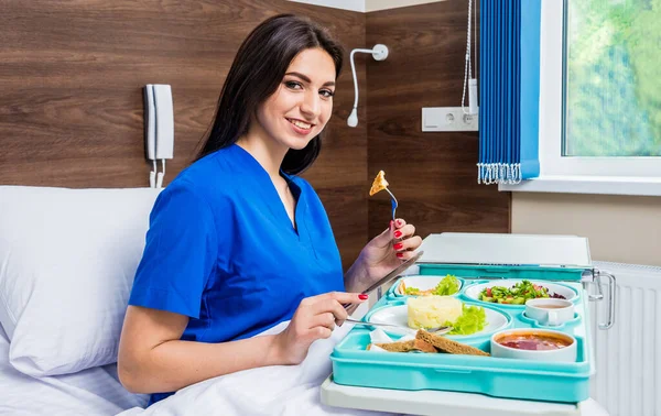 young woman eating in hospital, tray with breakfast for patient