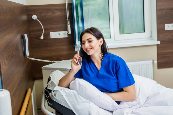 Patient talking on the phone in hospital bed. Young caucasian woman. Connected with nurse