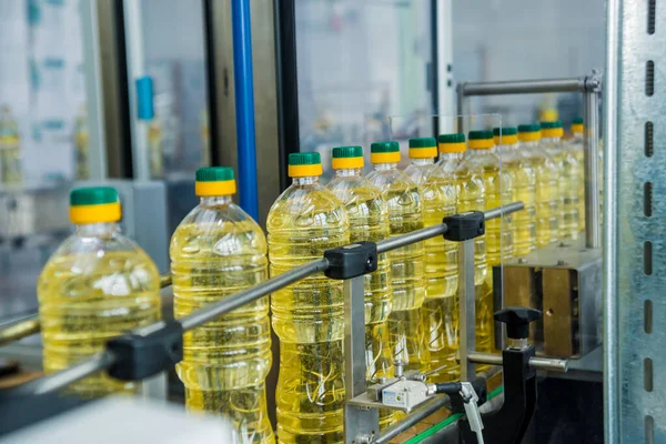 Bottling line of sunflower oil in bottles at plant, high technology concept, industrial background