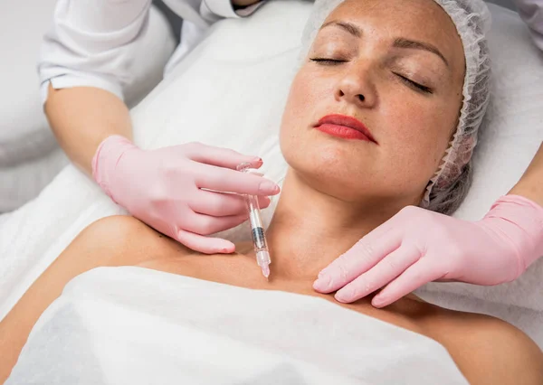 De arts cosmetoloog maakt de neklijn injecties procedure. Jonge vrouw in een schoonheidssalon. — Stockfoto
