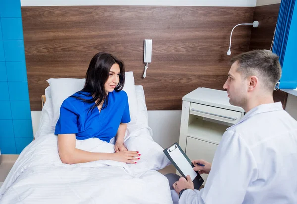 Traumatologist talking with young female patient in modern hospital