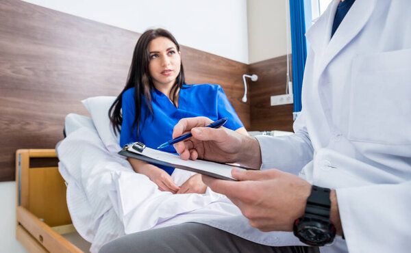 Traumatologist talking with young female patient in modern hospital. Medical concept