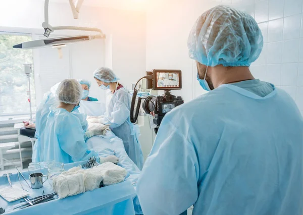 Ο εικονογράφος πυροβολεί τον χειρουργό και τους βοηθούς στο χειρουργείο με χειρουργικό εξοπλισμό. — Φωτογραφία Αρχείου