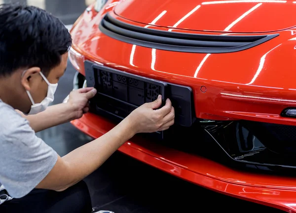 Technicien changer le numéro de plaque de voiture dans le centre de service . — Photo