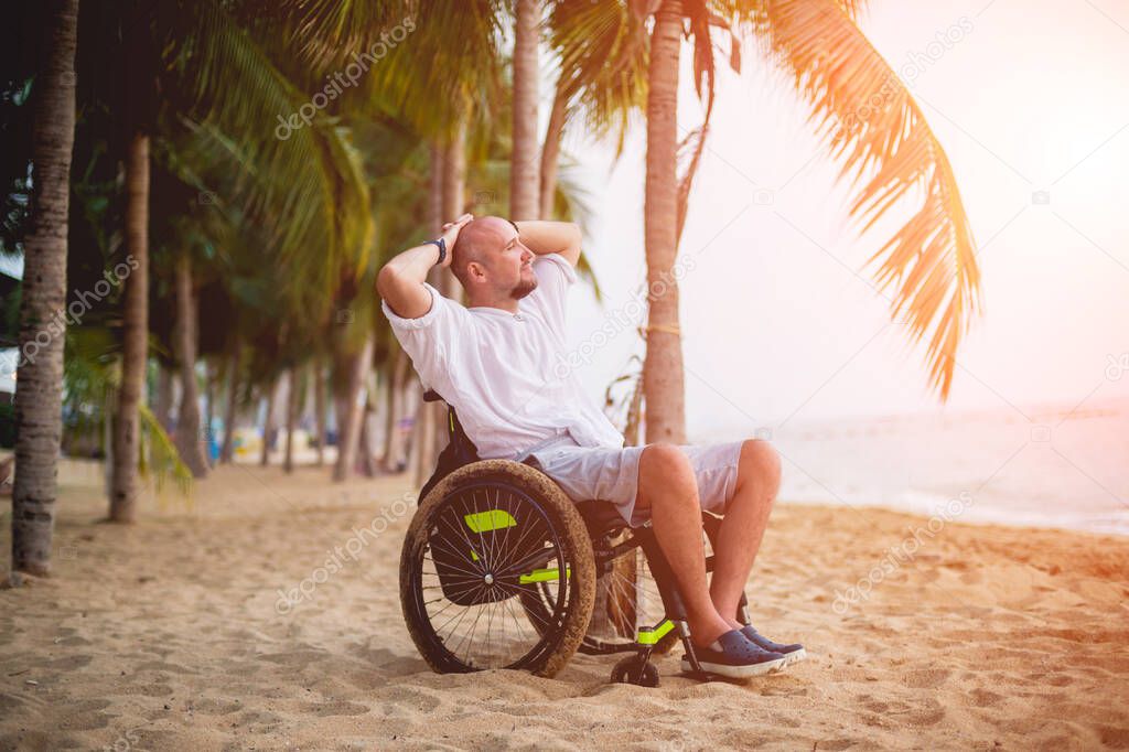 Disabled man in a wheelchair on the beach.