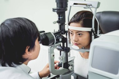 Bir göz doktoruna danışıyorum. Genç Asyalı kadın ve doktor 