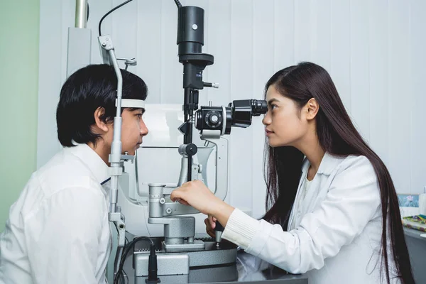 Bir göz doktoruna danışıyorum. Genç Asyalı erkek ve kadın doktor — Stok fotoğraf