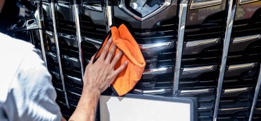 Car service worker polishing car with microfiber cloth. clipart