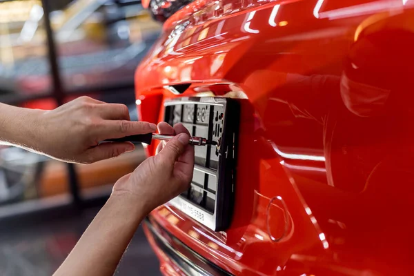 Técnico cambiando el número de placa del coche en el centro de servicio . — Foto de Stock