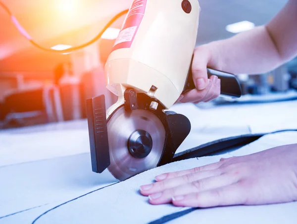 Vrouwelijke werknemer maakt gebruik van elektrische snijden stof machine. Productie van stoffen — Stockfoto