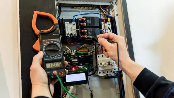 O homem está reparando a tensão do quadro com interruptores automáticos . — Fotografia de Stock