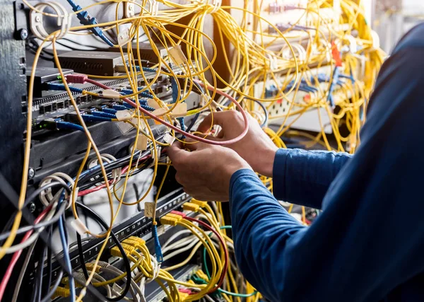 Engenheiro de rede a trabalhar na sala de servidores. Conectando cabos de rede aos switches — Fotografia de Stock