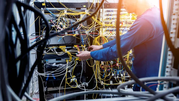 Síťový inženýr pracující v serverovně. Připojování síťových kabelů k přepínačům — Stock fotografie