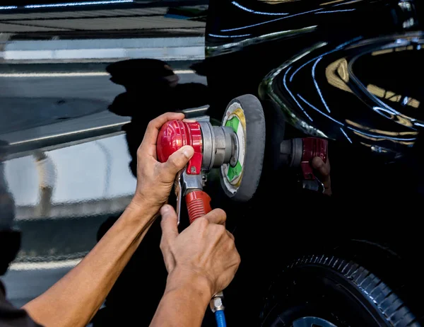 Der Arbeiter poliert ein Auto mit dem Elektrowerkzeug. — Stockfoto