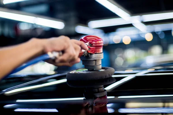 De arbeider poetst een auto met het elektrisch gereedschap. — Stockfoto