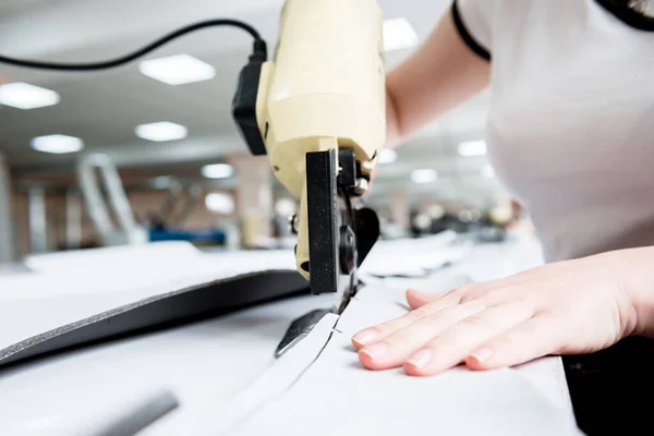 Trabajadora utiliza máquina de corte eléctrico de tela. Producción de la industria textil — Foto de Stock