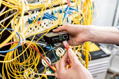 Sunucu odasında çalışan ağ mühendisi. Ağ kabloları anahtarlara bağlanıyor