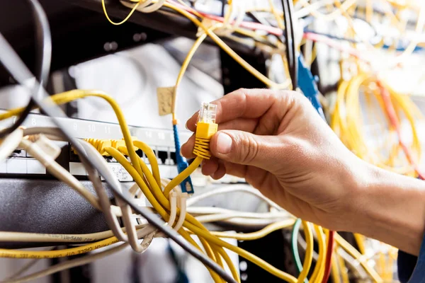 Network engineer working in server room. Connecting network cables to switches