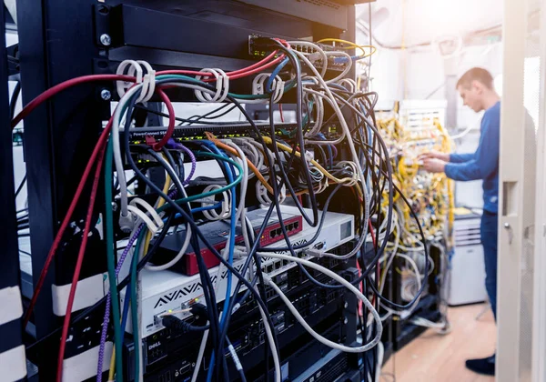 Network engineer working in server room. Connecting network cables to switches