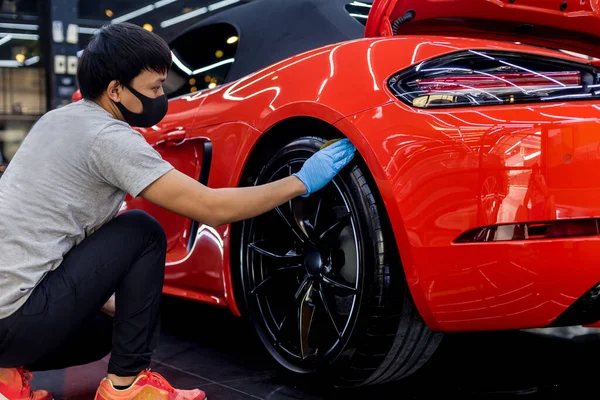 Trabajador de servicio de coche puliendo ruedas de coche con tela de microfibra. — Foto de Stock