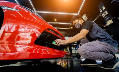 Araba servisi çalışanı bir araba detayına nano kaplama uyguluyor.