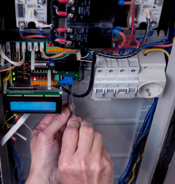 The man is repairing the switchboard voltage with automatic switches. — Stock Photo, Image