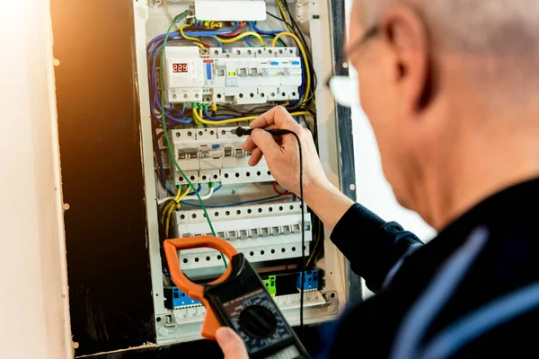 El hombre está reparando el voltaje de la centralita con interruptores automáticos . —  Fotos de Stock