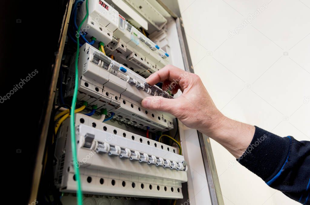 The man is repairing the switchboard voltage with automatic switches.