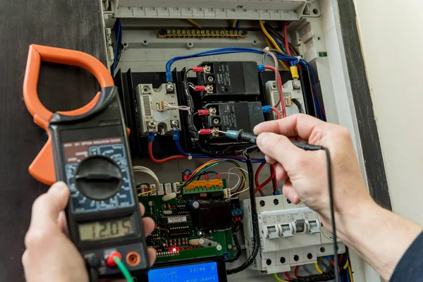 El hombre está reparando el voltaje de la centralita con interruptores automáticos . —  Fotos de Stock