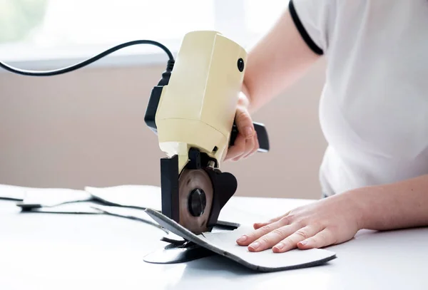 Kvinnlig arbetare använder elektrisk skärmaskin. Tillverkning inom textilindustrin — Stockfoto