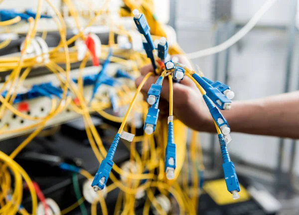 Network engineer working in server room. Connecting network cables to switches